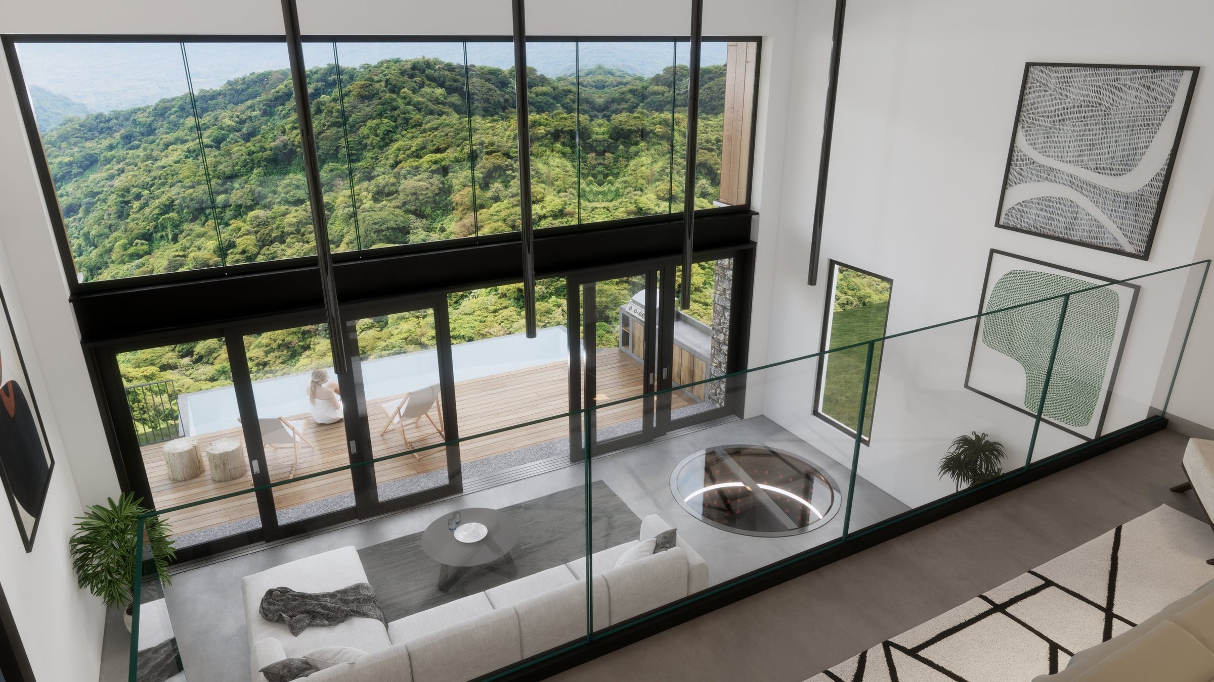 Living room with glass railing overlooking a large window with a view of lush green hills. The room has a white sofa with a throw blanket, a round coffee table, and wall art. Outside on the balcony, a woman sits on a chair near a barbecue grill, enjo