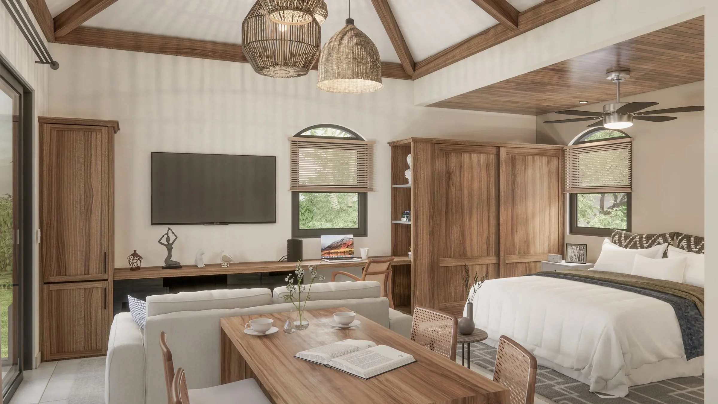 Bright living space with a wooden ceiling and large windows. Contains a bed with a white comforter, a chair near a desk with a laptop, and a dining table with cups and an open book.