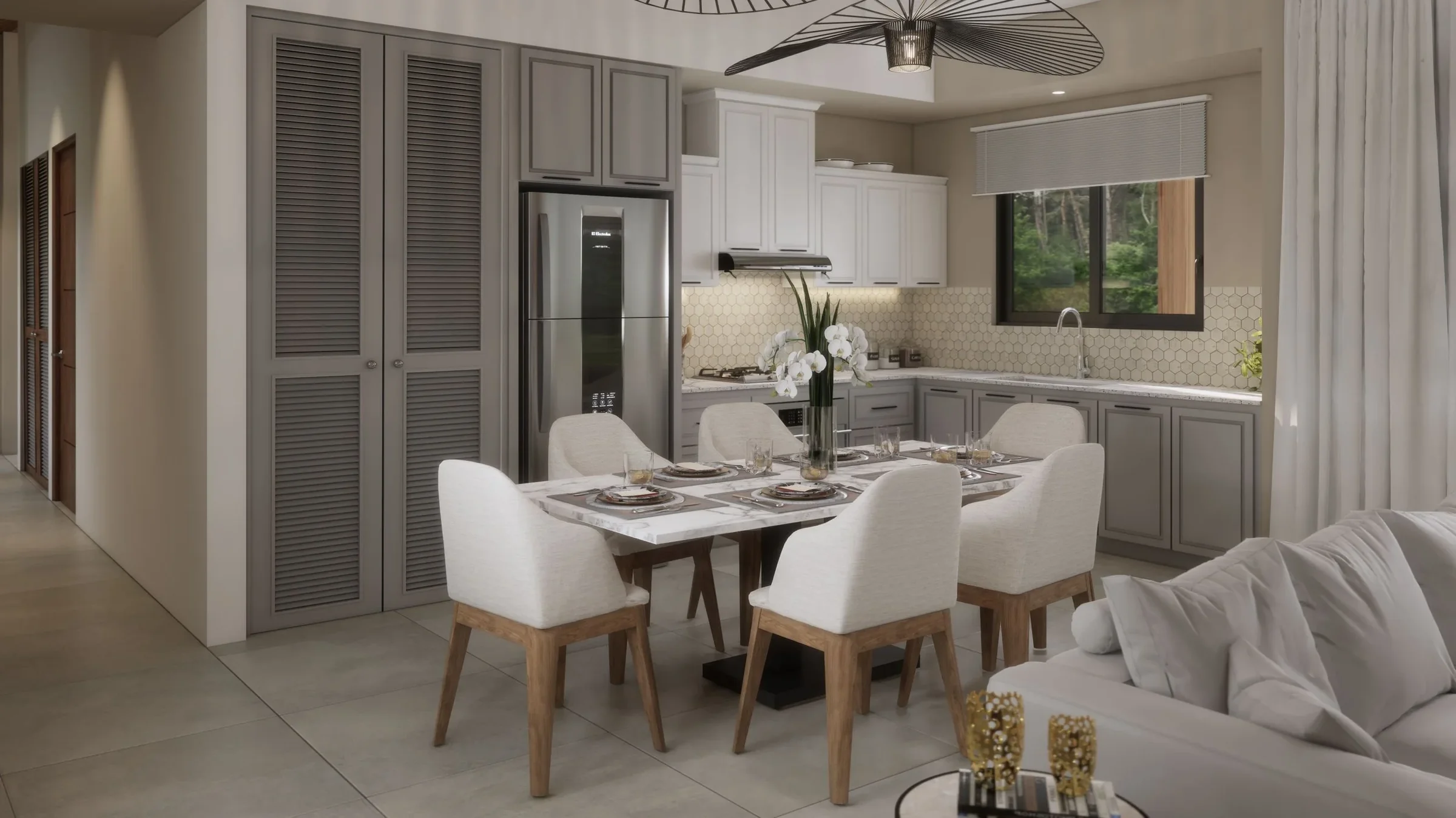 Dining area with a marble table set with plates, glasses, and white napkins, surrounded by eight upholstered chairs, nearby is a sofa with pillows, in an open kitchen with gray cabinets, stainless steel refrigerator, window, and modern lighting.