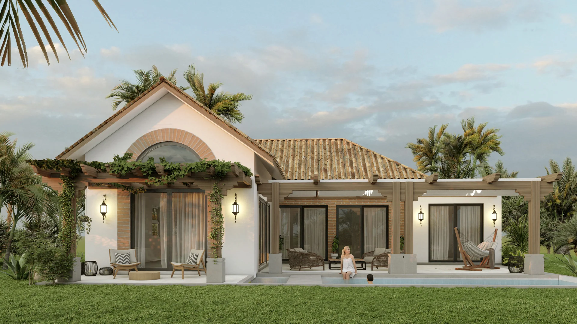 Exterior view of a modern house with a tiled roof, white walls, and large glass sliding doors. The house has a patio with outdoor seating, a pergola with climbing plants, and a swimming pool with two people relaxing in and around it. Tall palm trees