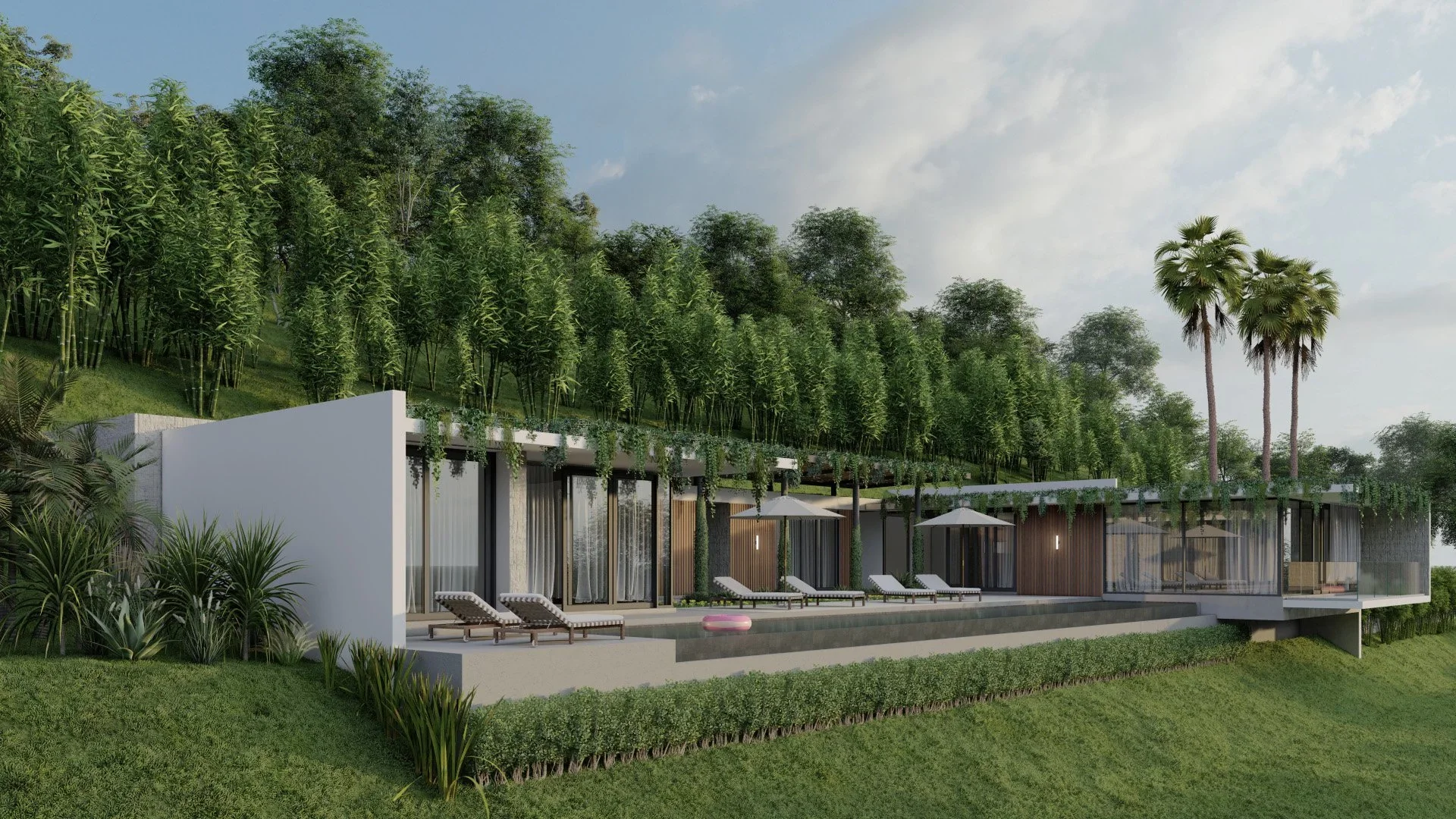 Modern hillside house with large glass windows, outdoor lounge chairs, umbrellas, a swimming pool, surrounded by lush greenery and tall trees under a partly cloudy sky.